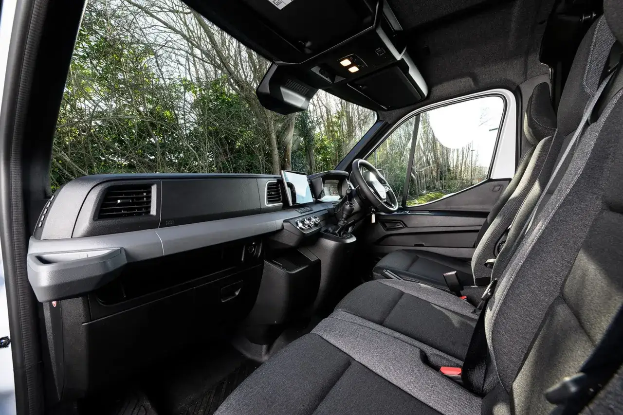 Interior del Renault Master con asientos de tela gris, volante, pantalla táctil y tablero moderno.