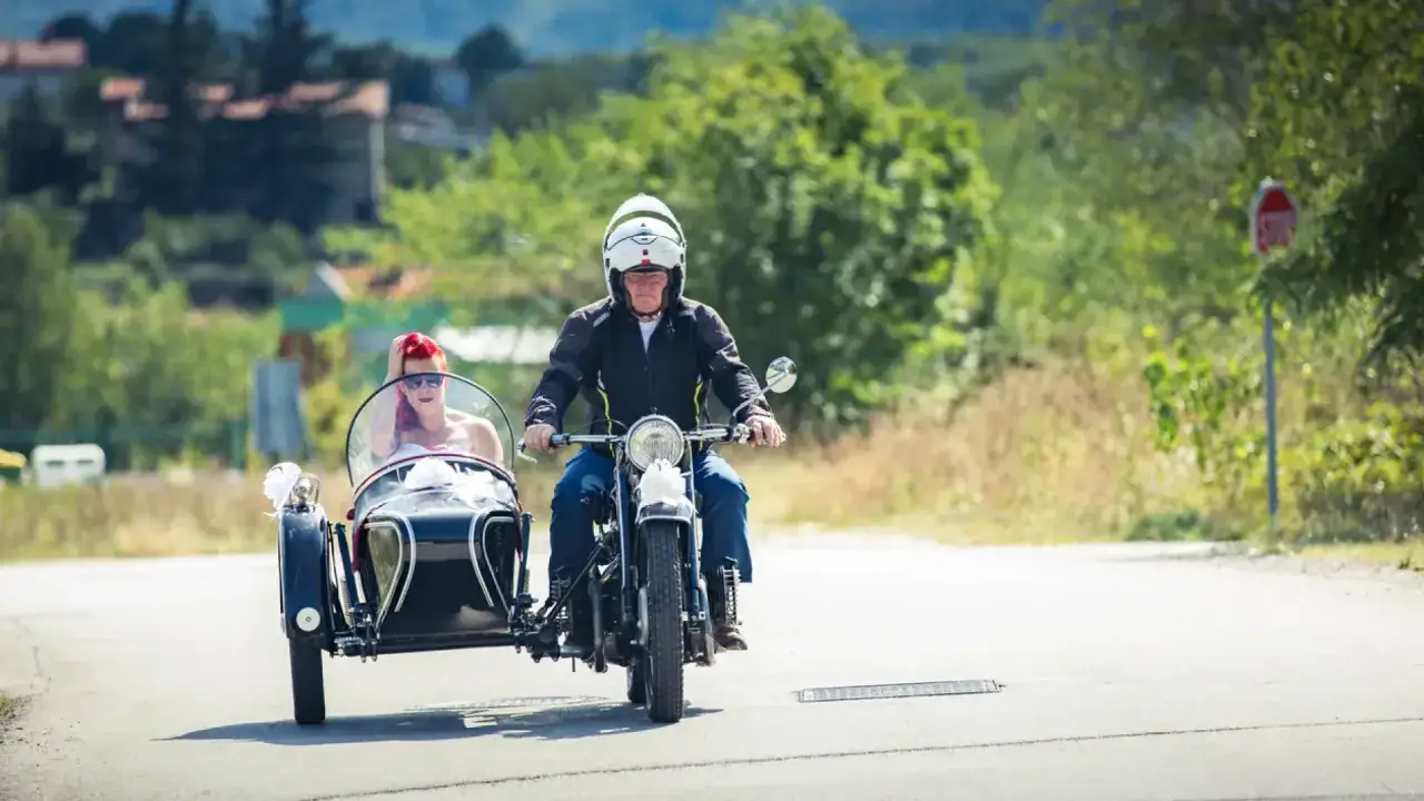 Hombre conduce motocicleta con sidecar donde va una mujer. Un permiso a motocicletas con sidecar es necesario para circular.