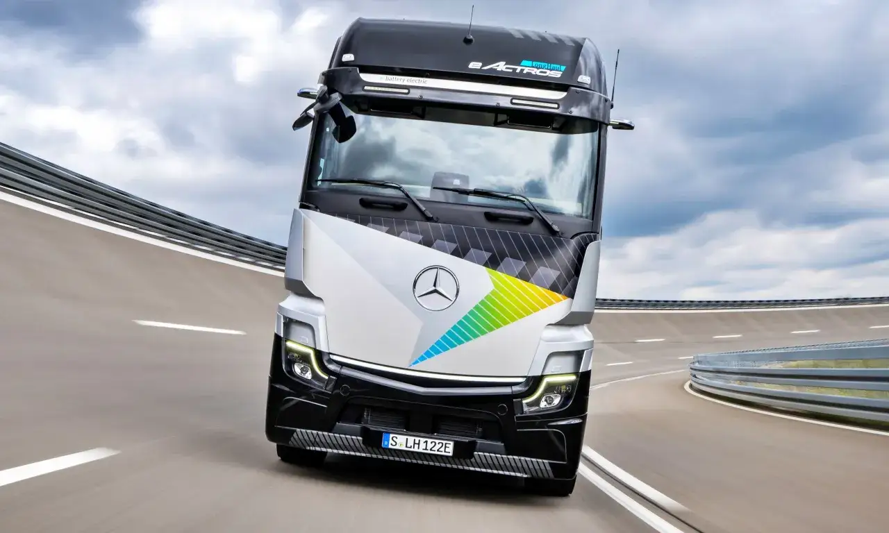 El eActros L, un camión eléctrico de Mercedes-Benz, avanza por una carretera con un diseño futurista y colores vibrantes.