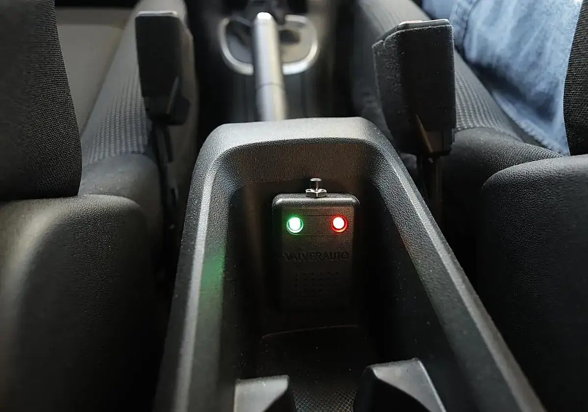 Interior de un coche de autoescuela con dispositivo VALVERAUTO y luces indicadoras verdes y rojas.