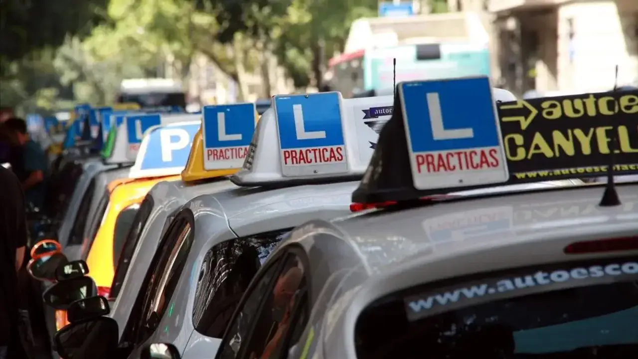 Fila de coches de autoescuela con letreros de 