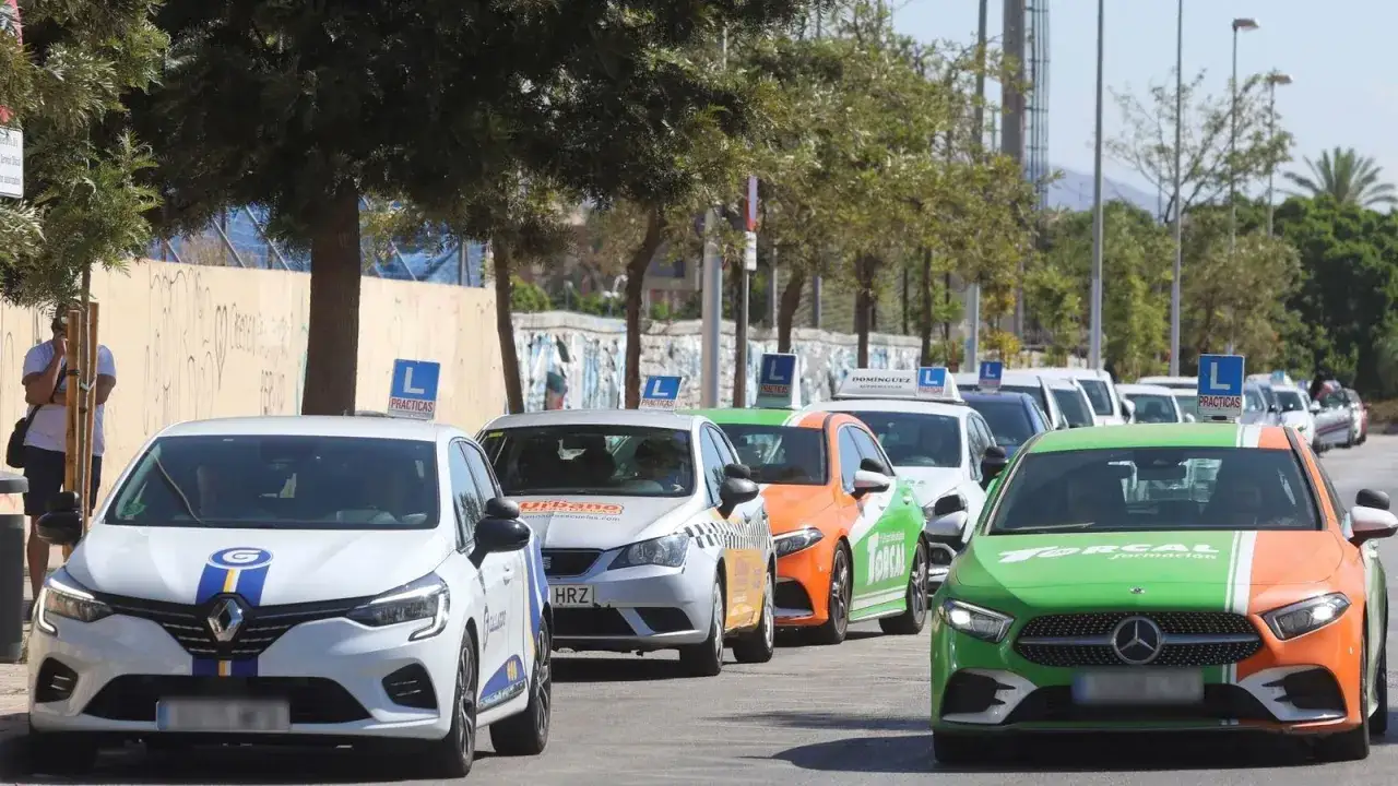 Fila de coches de autoescuela con letreros de 