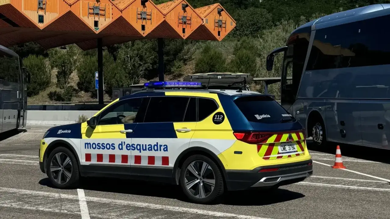 Coche de polic&iacute;a de los Mossos d'Esquadra junto a un autob&uacute;s, posiblemente controlando una multa por exceso de peso.