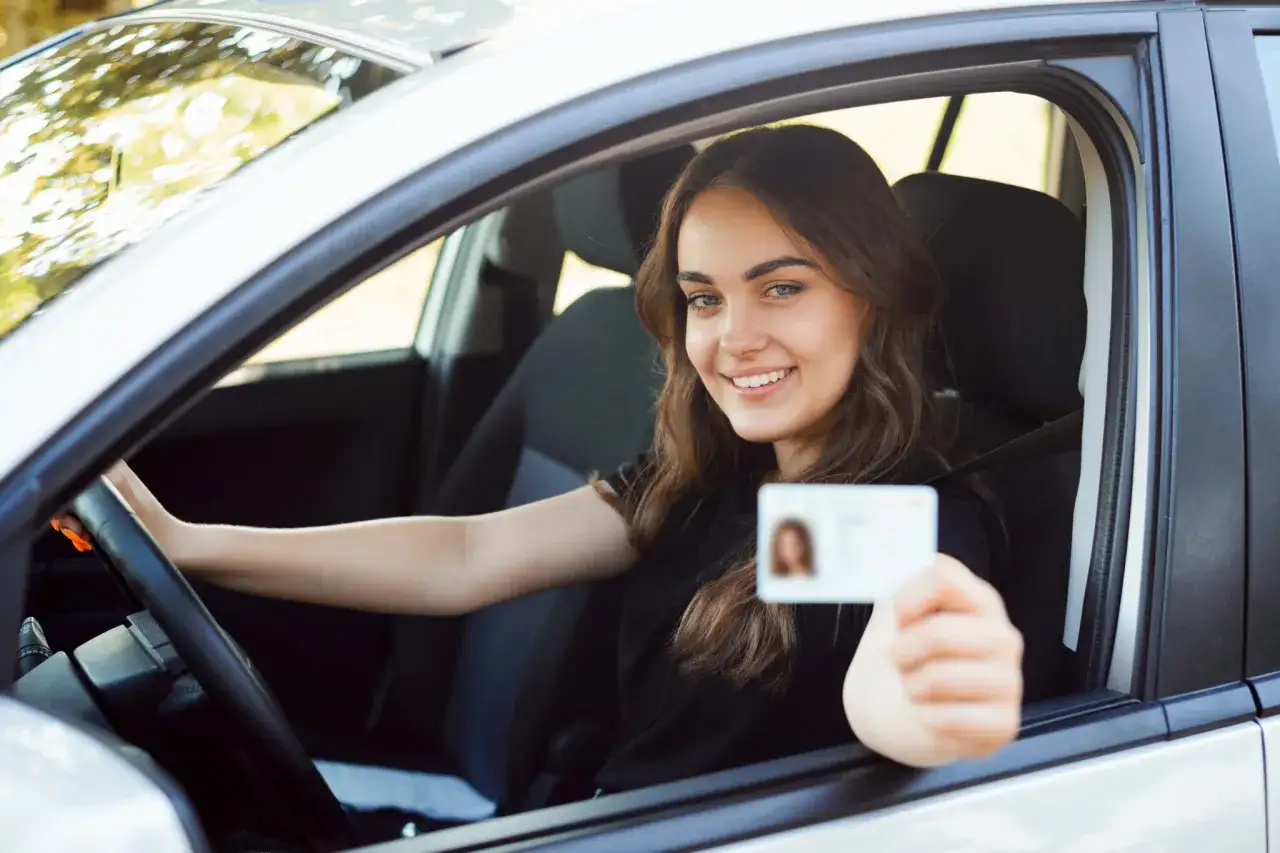 Joven sonriente muestra su carnet de conducir, lista para saber que carnet se necesita para conducir un minibus.