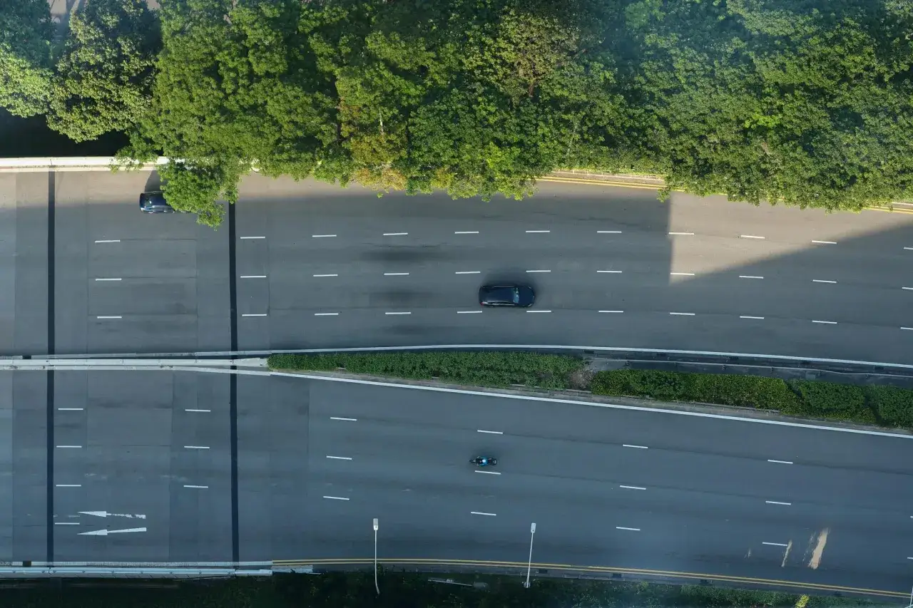 Vista aérea de una carretera con un coche y una moto, mostrando la velocidad de fluidez de una vía rodeada de vegetación.