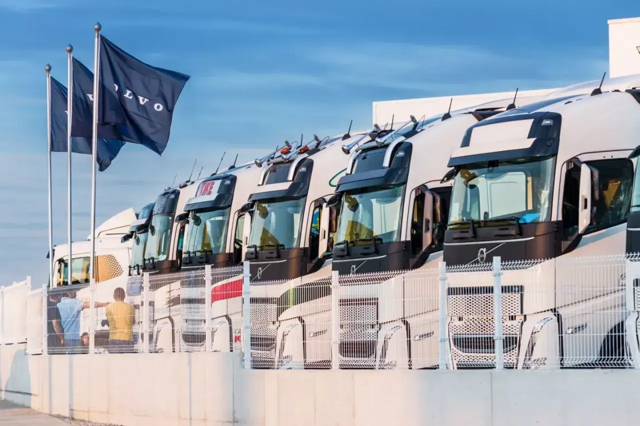 Fila de camiones Volvo listos para la carretera. Banderas de Volvo ondean al viento.
