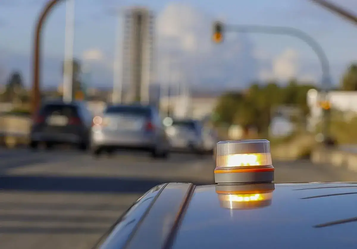 Baliza de emergencia naranja en un coche, lista para señalizar. Los triangulos de preseñalizacion son esenciales para la seguridad vial.