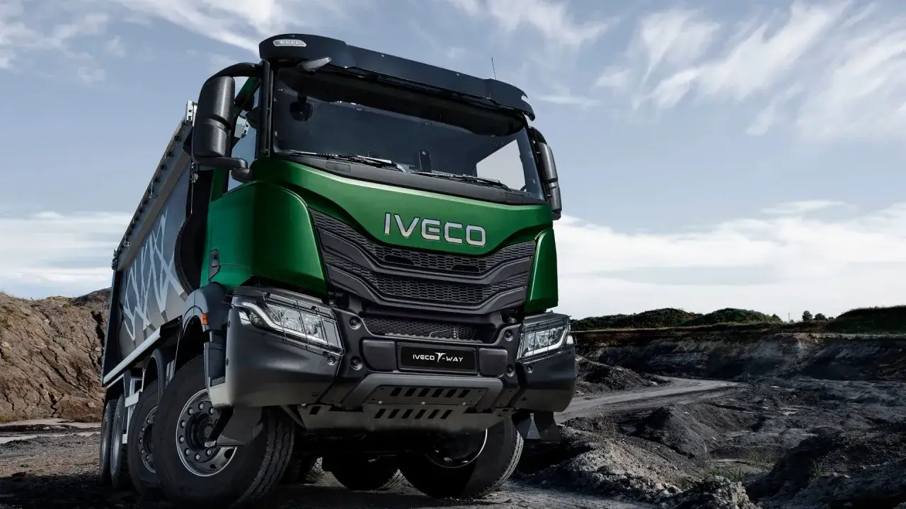 Camión Iveco T-Way verde, listo para la acción en un terreno accidentado bajo un cielo nublado.