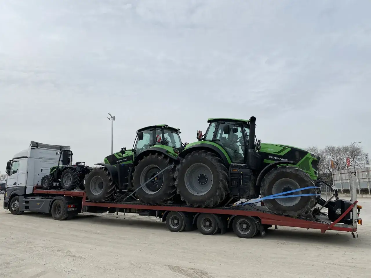 Camión transportando tractores verdes. El precio de estos potentes vehículos agrícolas es una inversión para el futuro.