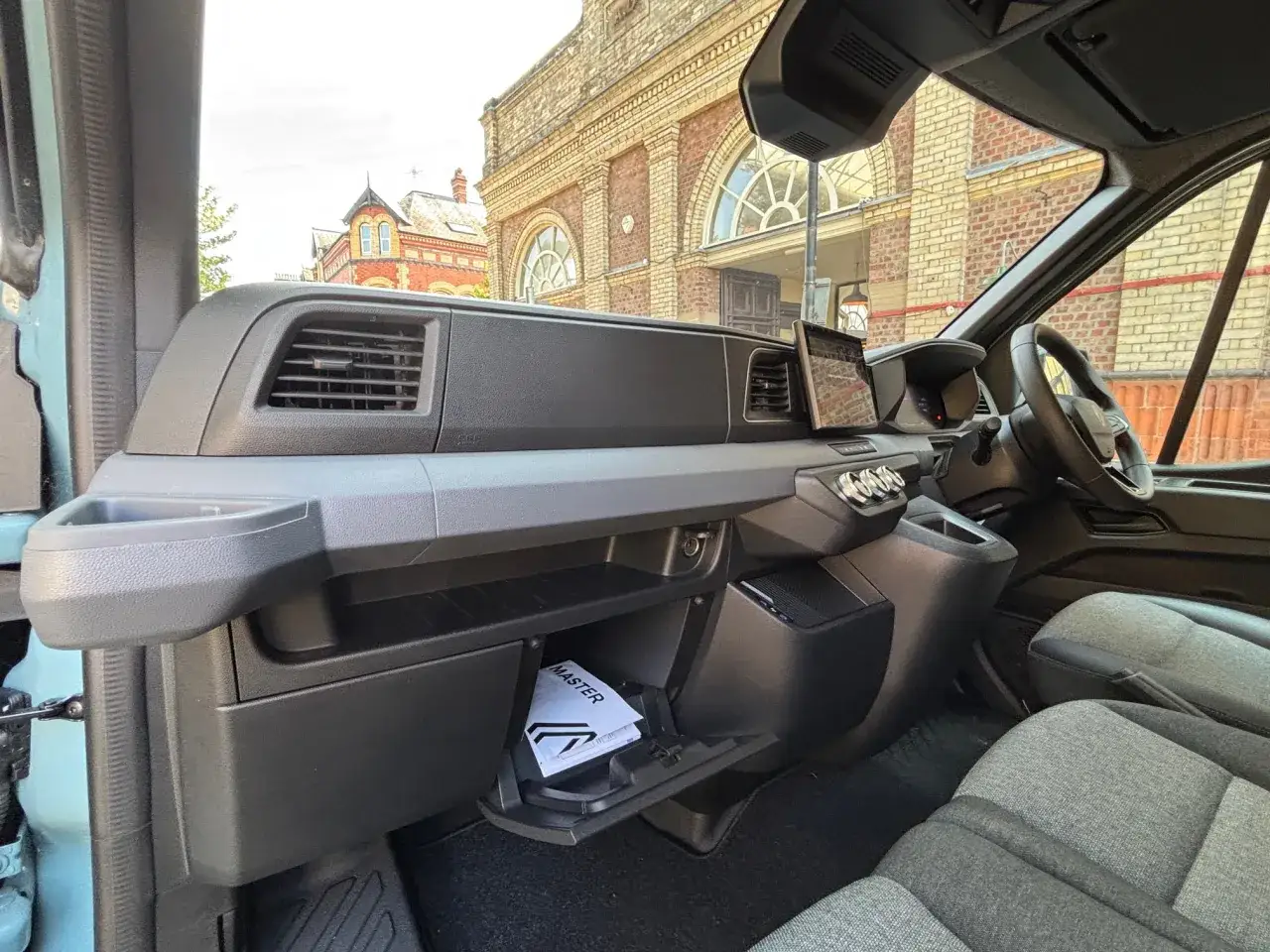 Interior del Renault Master con pantalla táctil, aire acondicionado y asientos cómodos. El manual del propietario, con la palabra 