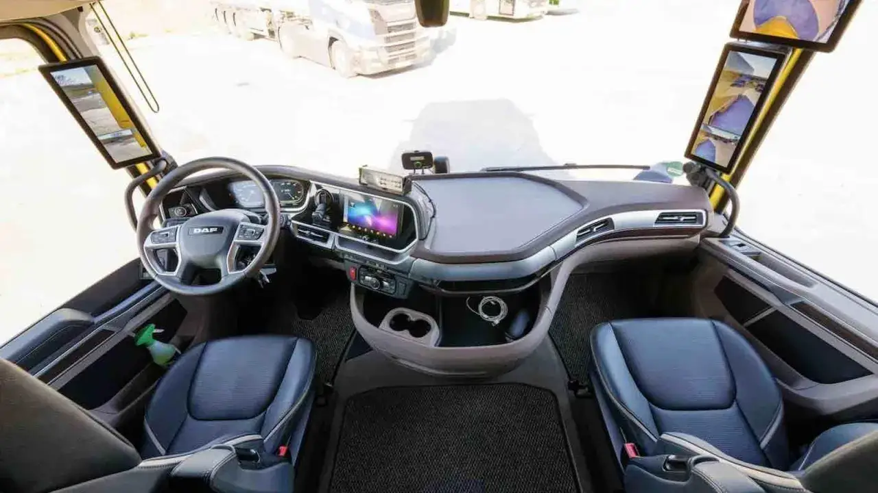 Interior del DAF XG Plus: asientos de cuero, volante multifunción, pantalla táctil central y monitores digitales.