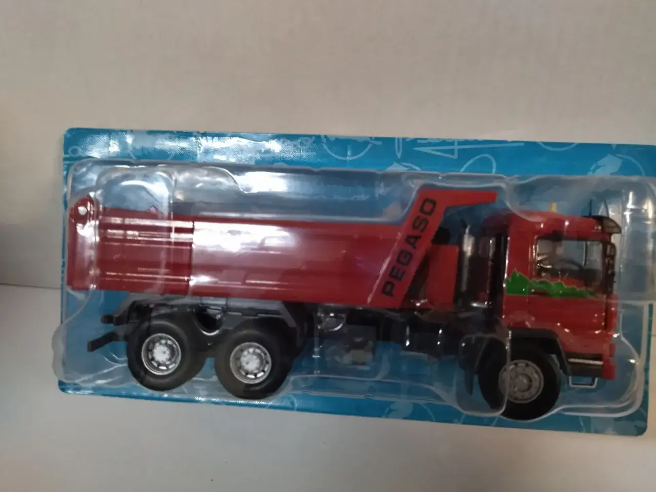 Camión volquete rojo de juguete, modelo Pegaso Trakker, en su embalaje original.