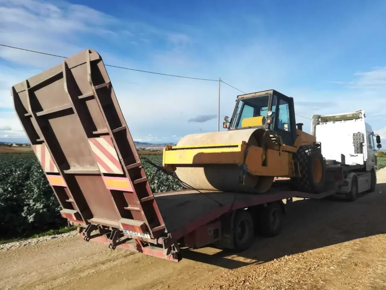 Compactador amarillo sobre g&oacute;ndola, listo para transporte. Consulta el precio km g&oacute;ndola para mover maquinaria pesada.
