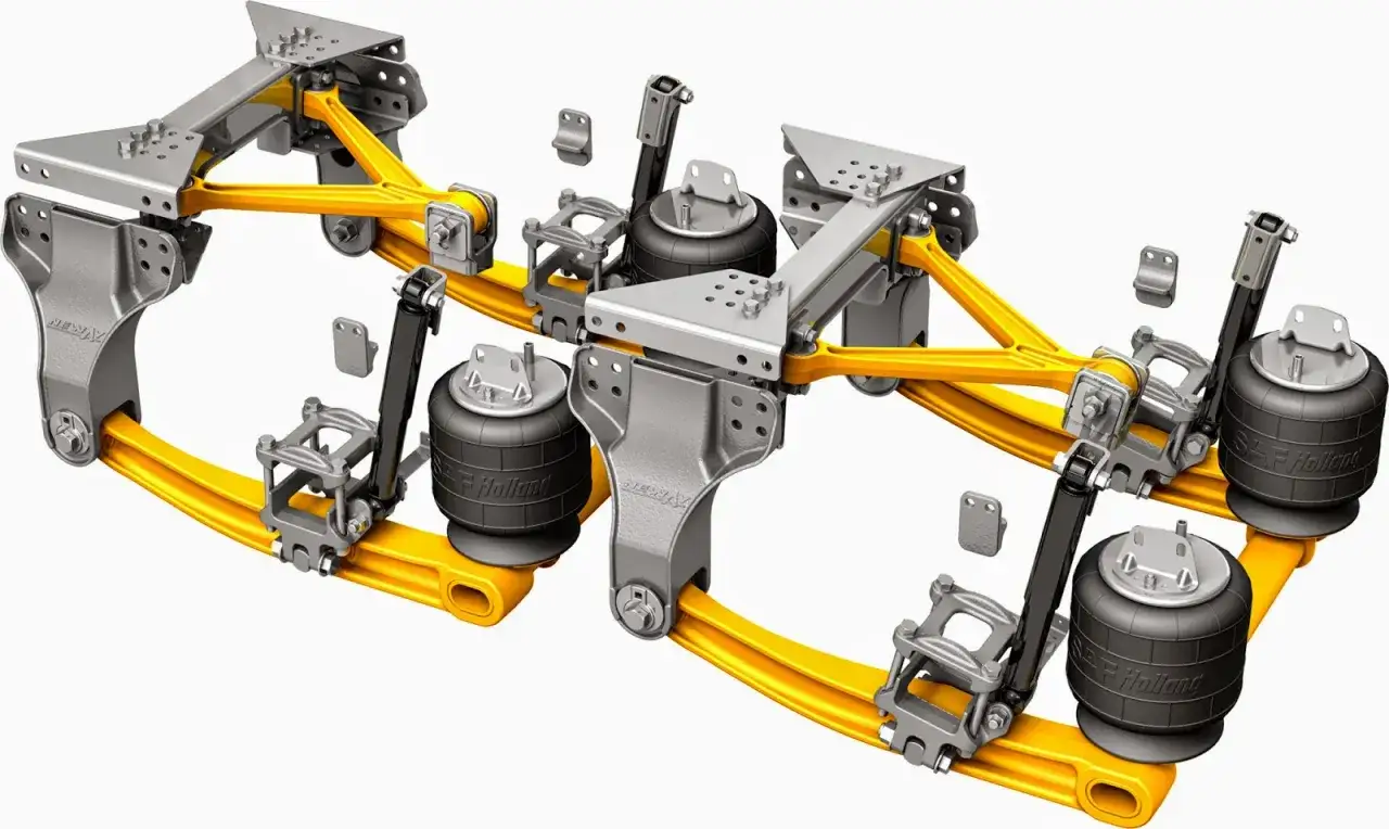 Detalle del eje tandem de un camión, con suspensión neumática y componentes de metal amarillo y gris.
