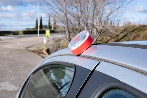 Baliza de emergencia roja y blanca en el techo de un coche plateado, lista para evitar una multa.